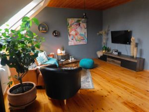 Wohnzimmer mit Sofa, Sessel, Wohnzimmer-Tisch, Sideboard und Smart-Tv