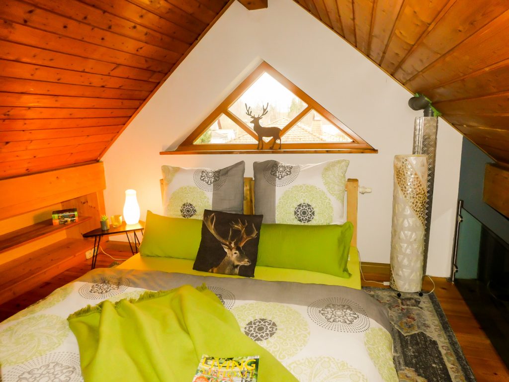 Nahaufnahme des Bettes, Links steht ein Beistelltisch und rechts vom Bett eine große Lampe